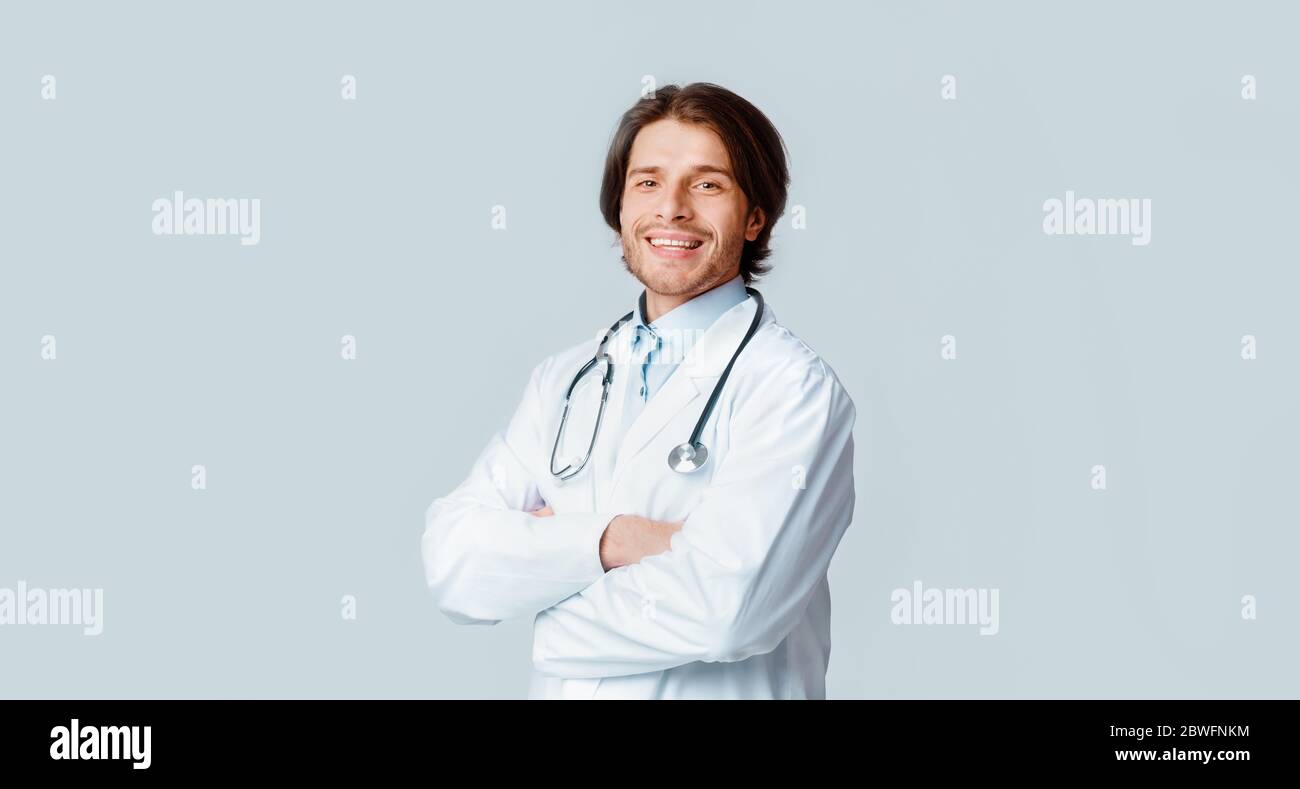 Portrait of handsome medical professional with stethoscope posing over light background Stock Photo
