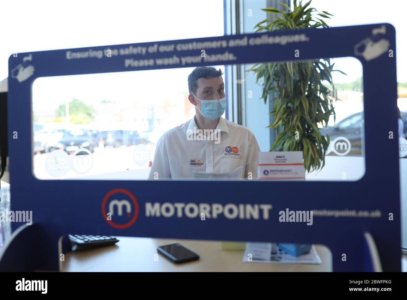 Satff work behind protective shields at Motorpoint Chingford car dealer