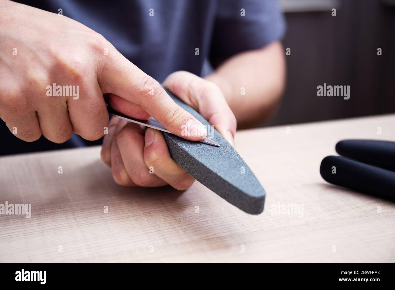 https://c8.alamy.com/comp/2BWFRA8/close-up-strong-male-hands-sharpen-a-kitchen-metal-knife-with-a-grindstone-home-household-knife-sharpening-2BWFRA8.jpg