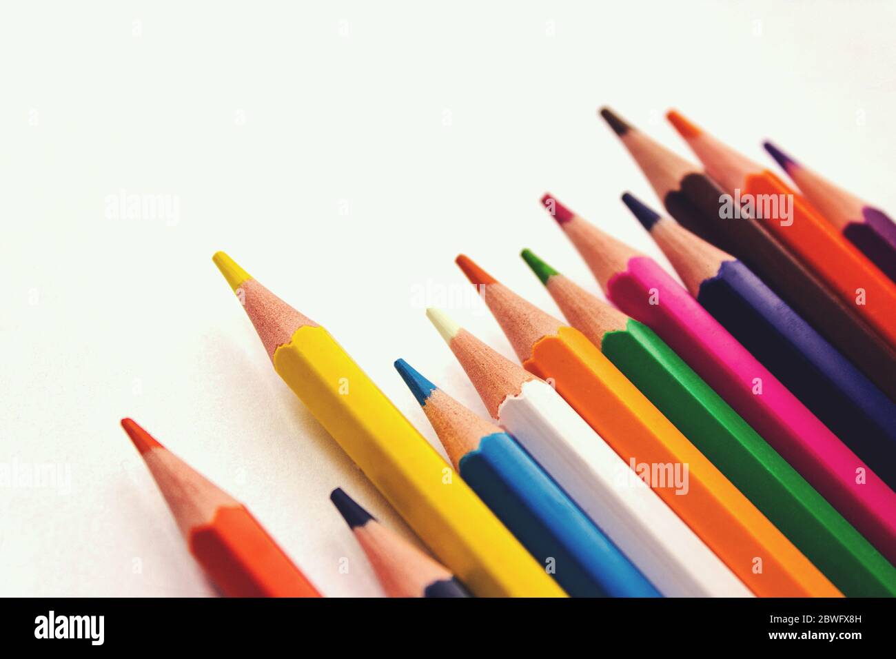 School notebook, Colored pencils in row on white background Stock Photo