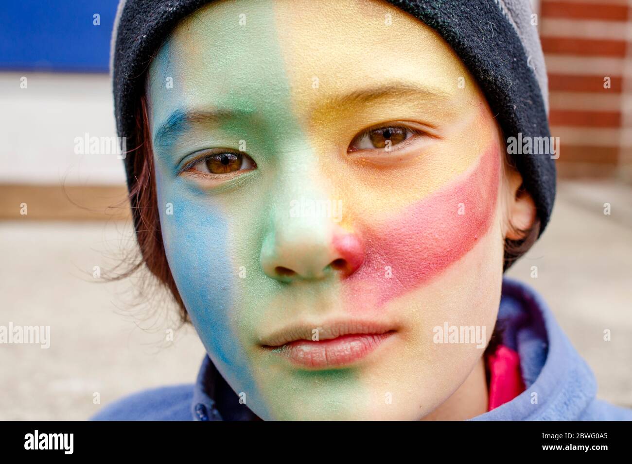 Portrait of beautiful boy with colorful face paint and direct gaze Stock Photo