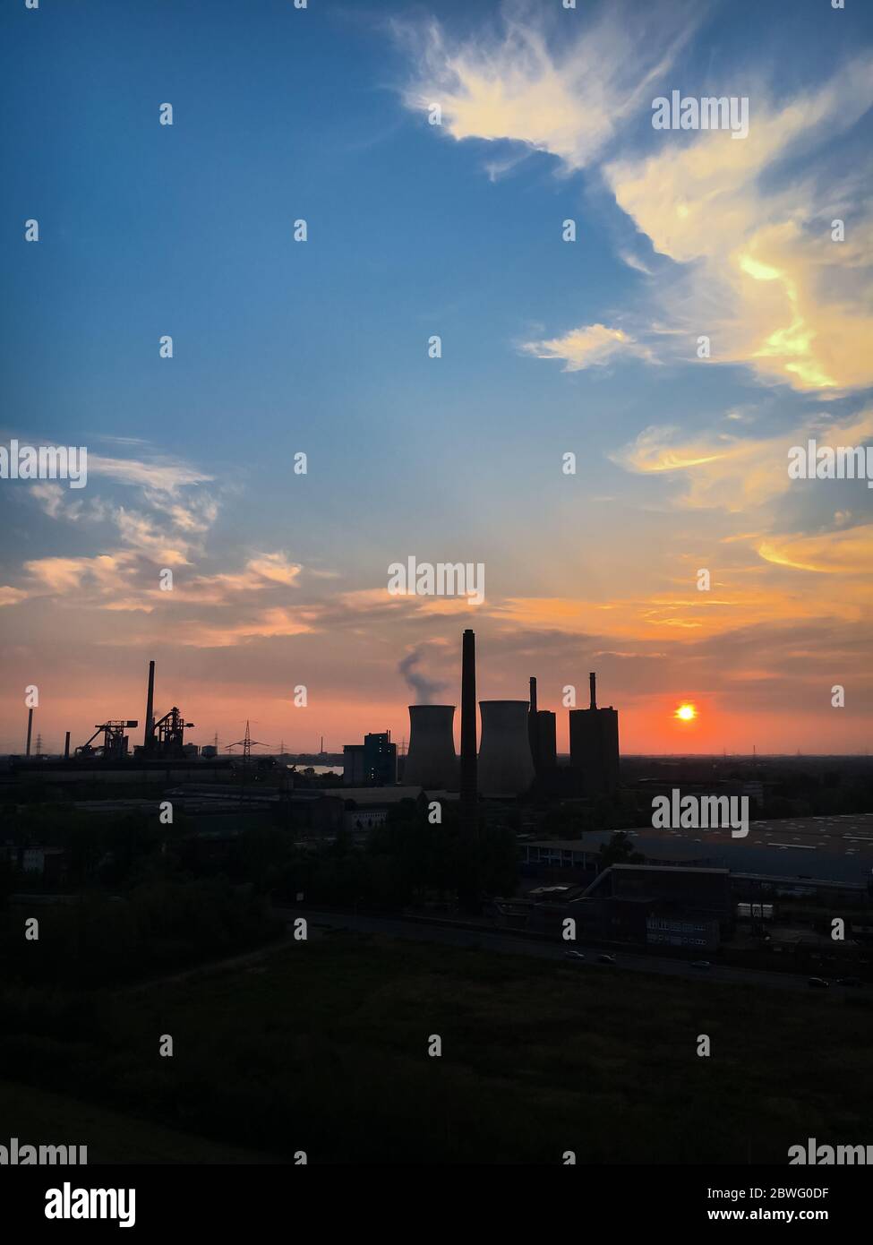 Duisburg, Germany – August 28, 2018: Scenic view of power station and cooling tower of „RWE Power AG“ at sunset against colorful sky Stock Photo