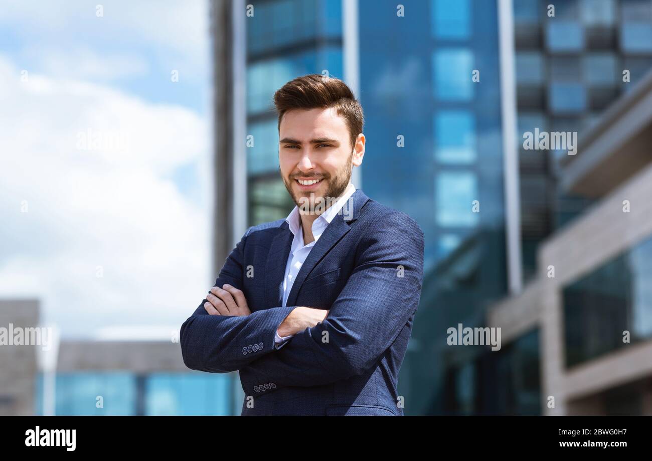 Handsome businessman with crossed arms standing in front of office ...