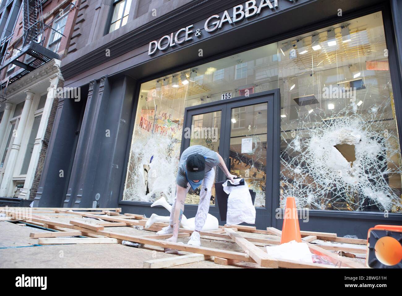 New York, New York, USA. 1st June, 2020. A volunteer from the SoHo neighborhood helps clean up the destruction from The Dolce Gabbana store in Soho which was looted early Monday morning in New York, New York, Many other er New York Stores were also damaged and over 200 arrest were made from the Soho looting Credit: Brian Branch Price/ZUMA Wire/Alamy Live News Stock Photo