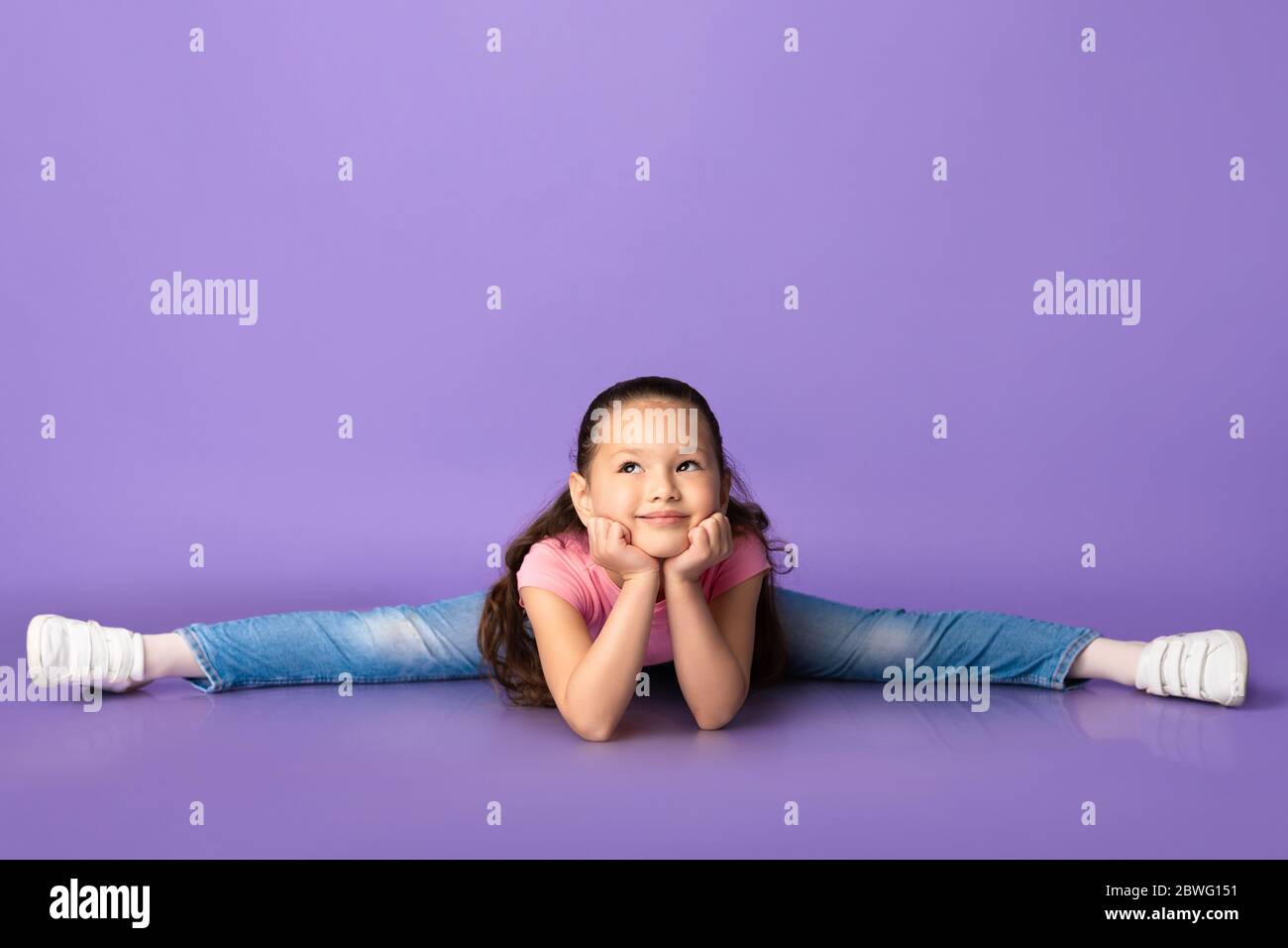 Two cute and handsome little girls doing front splits on violet