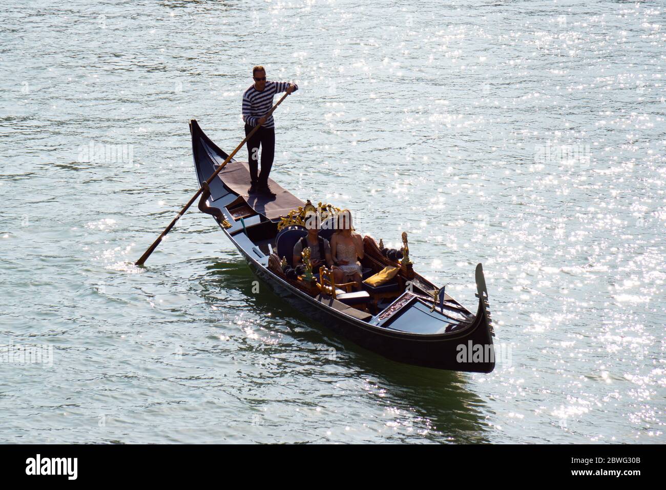 Venice, Italy - October, 2019: Tourists enjoying a gondola ride in the lagoons of Venice. Stock Photo
