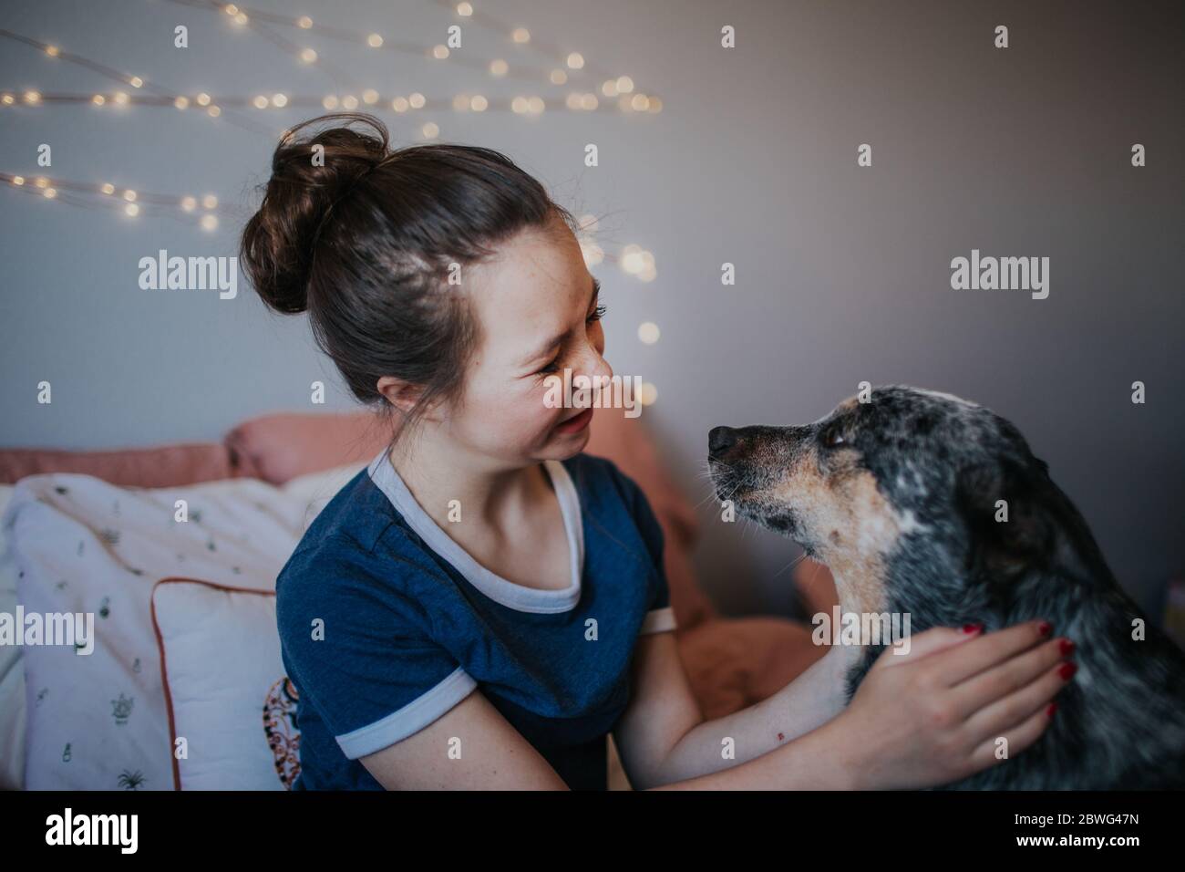 tween girl playing with her dog on her bed Stock Photo