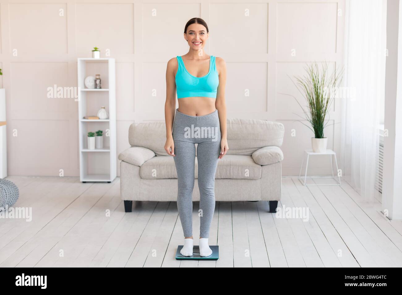 https://c8.alamy.com/comp/2BWG4TC/slim-woman-weighing-herself-standing-on-scales-at-home-2BWG4TC.jpg