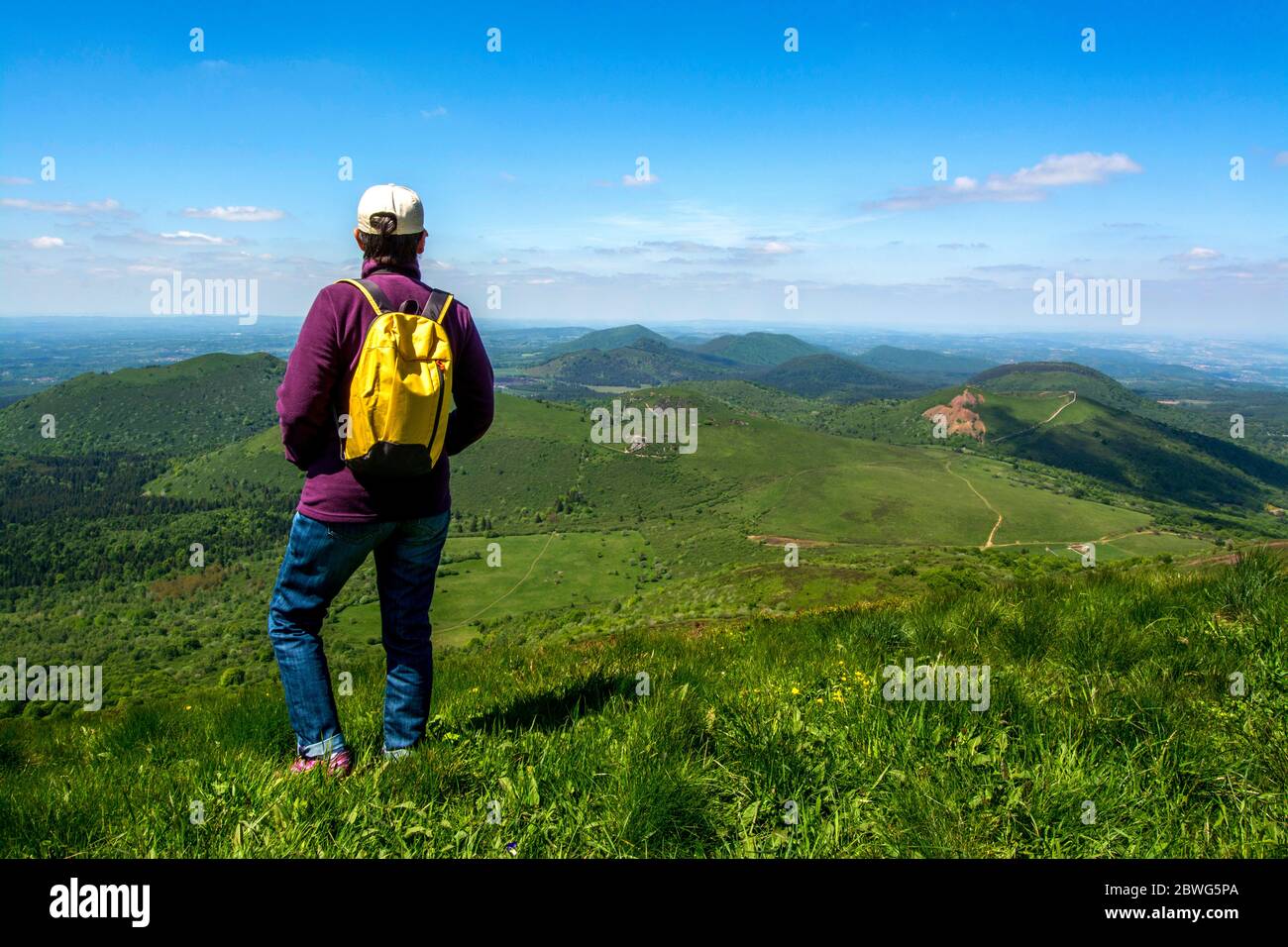 Hiker looking at view of Volcanic Chaine des Puys, UNESCO World Heritage, Puy de Dome, Auvergne-Rhone-Alpes, France Stock Photo
