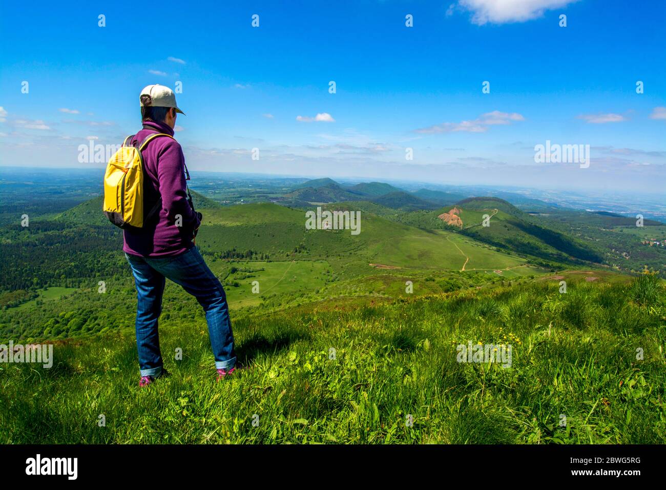 Hiker looking at view of Volcanic Chaine des Puys, UNESCO World Heritage, Puy de Dome, Auvergne-Rhone-Alpes, France Stock Photo