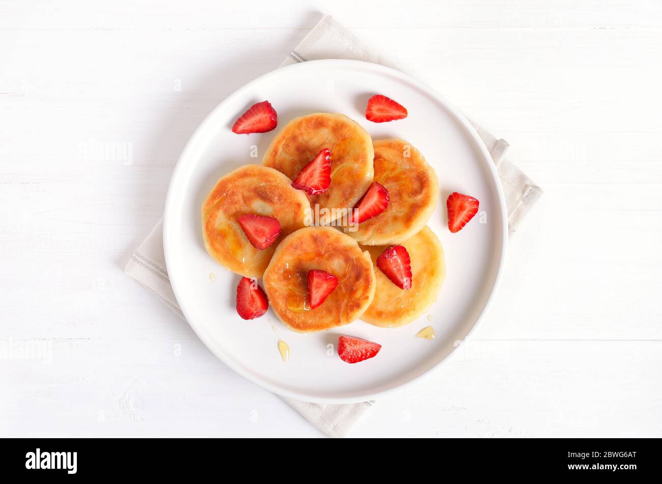 Homemade pancakes with cottage cheese and strawberry slices, syrniki.  Top view, flat lay Stock Photo