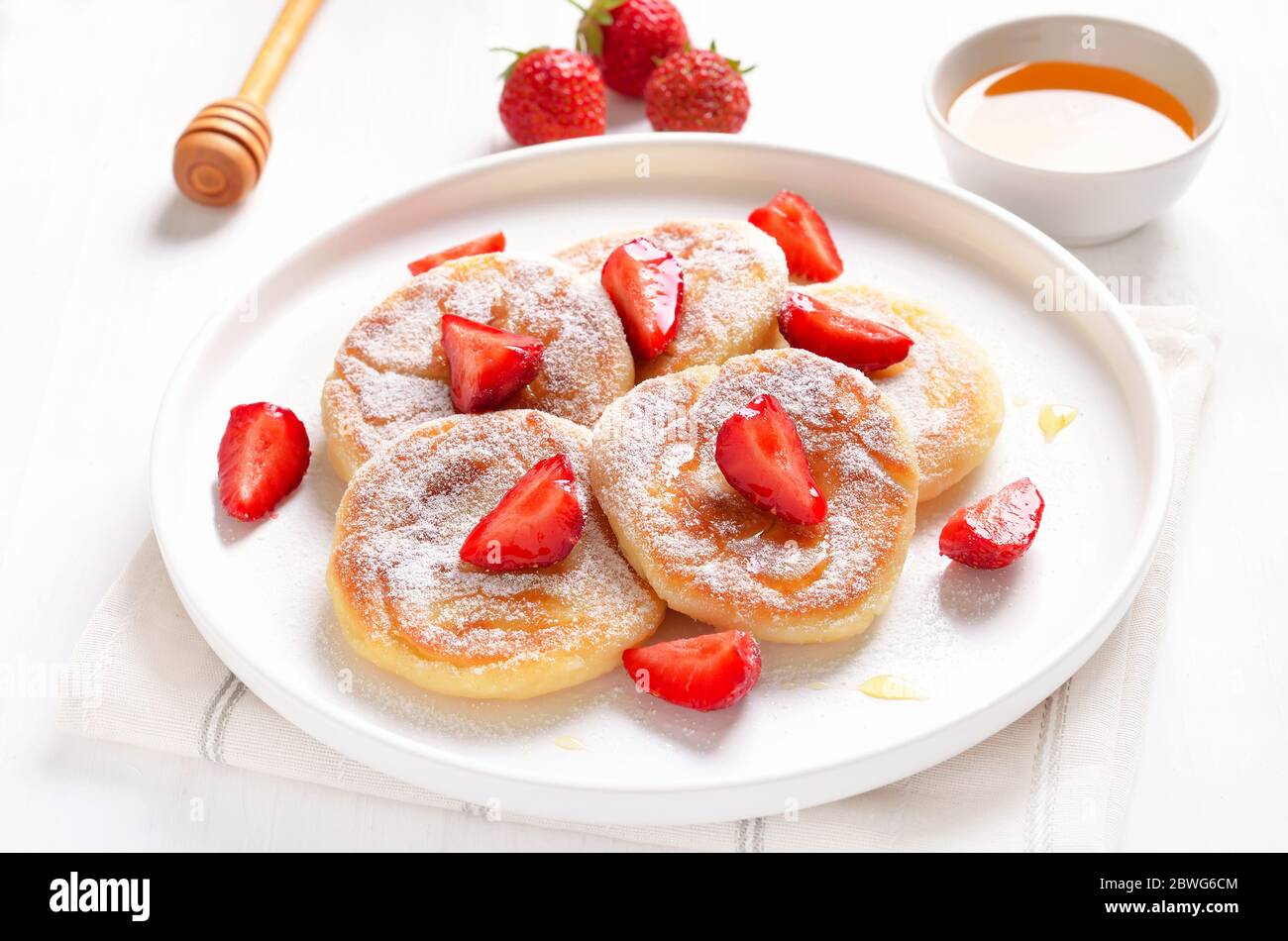 Homemade pancakes with cottage cheese and strawberry slices, syrniki, close up view Stock Photo