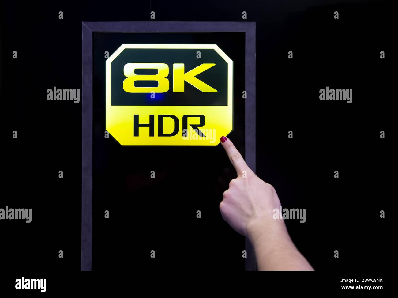 Moscow, Russia - October 04, 2019: female finger points to 8k hdr quality icon. background is black Stock Photo