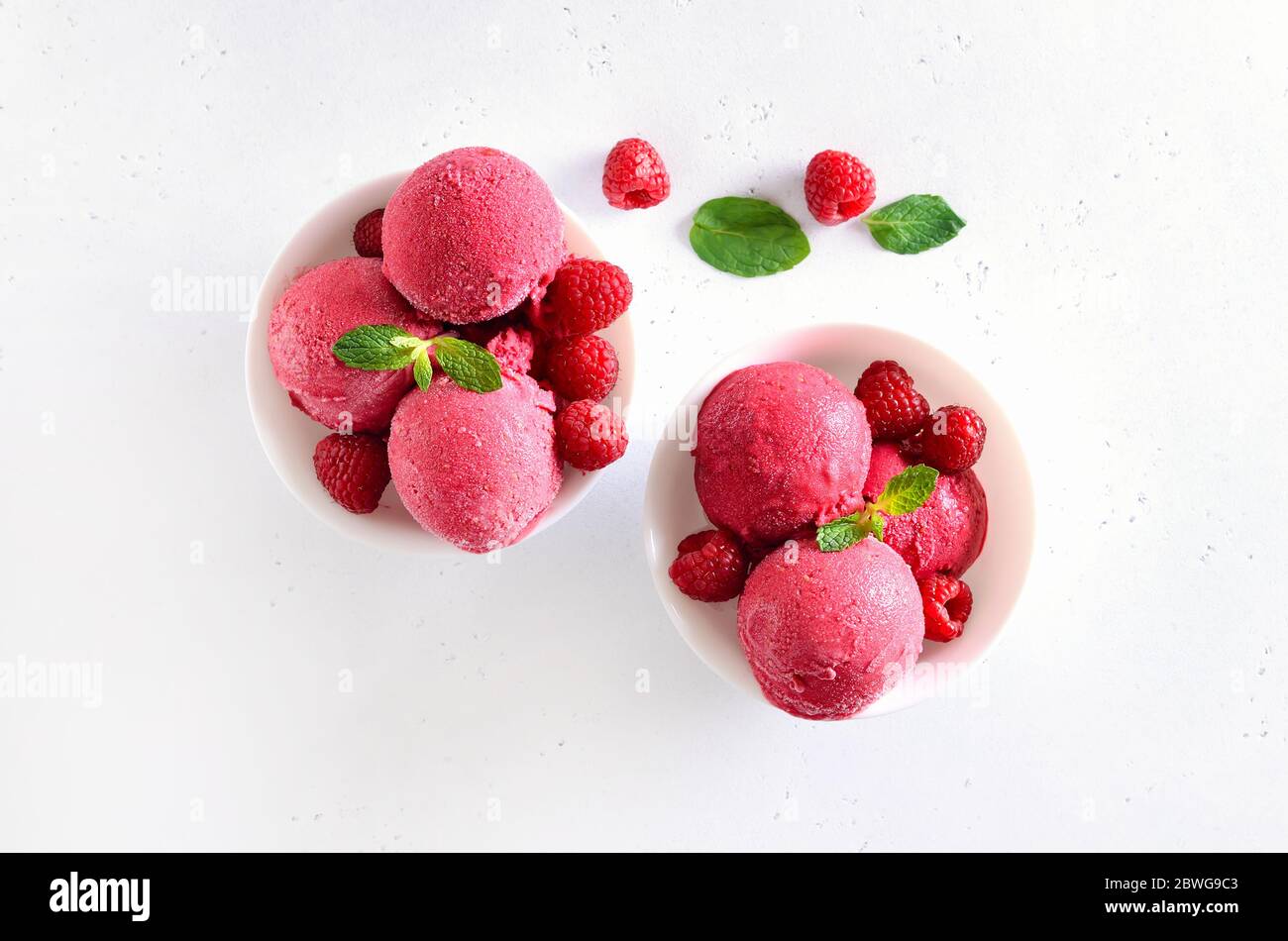 Raspberry ice cream scoop with fresh raspberries in white bowl. Cold summer dessert. Top view, flat lay Stock Photo