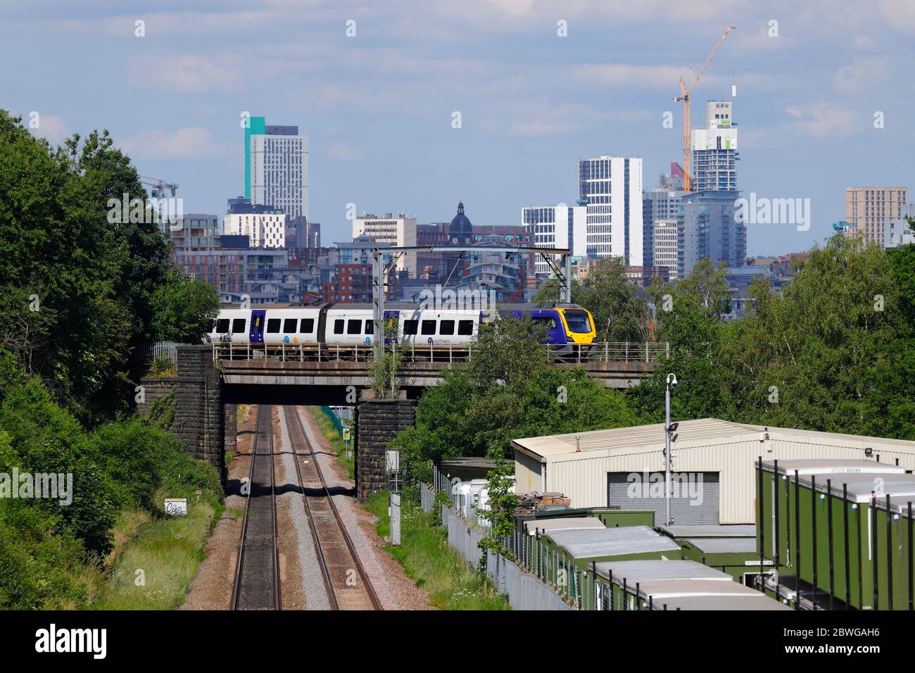 A rail class 331 train operated by Northern Rail, passes in front of Leeds Skyline Stock Photo