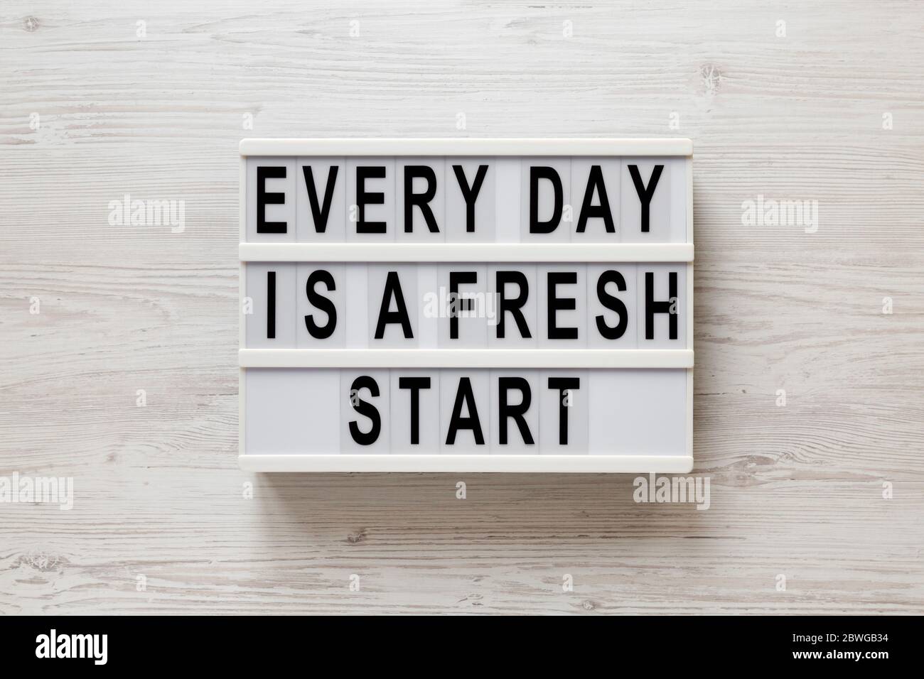 'Every day is a fresh start' words on a lightbox on a white wooden surface, top view. Overhead, from above, flat lay. Stock Photo