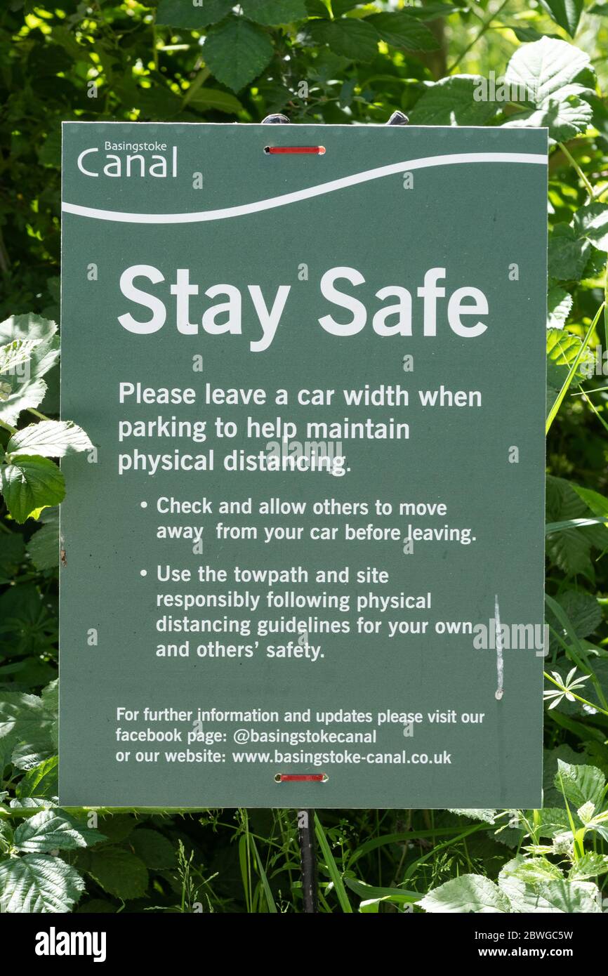 Stay safe on a notice by the Basingstoke Canal with information and rules about keeping safe during the 2020 coronavirus covid--19 pandemic, UK Stock Photo