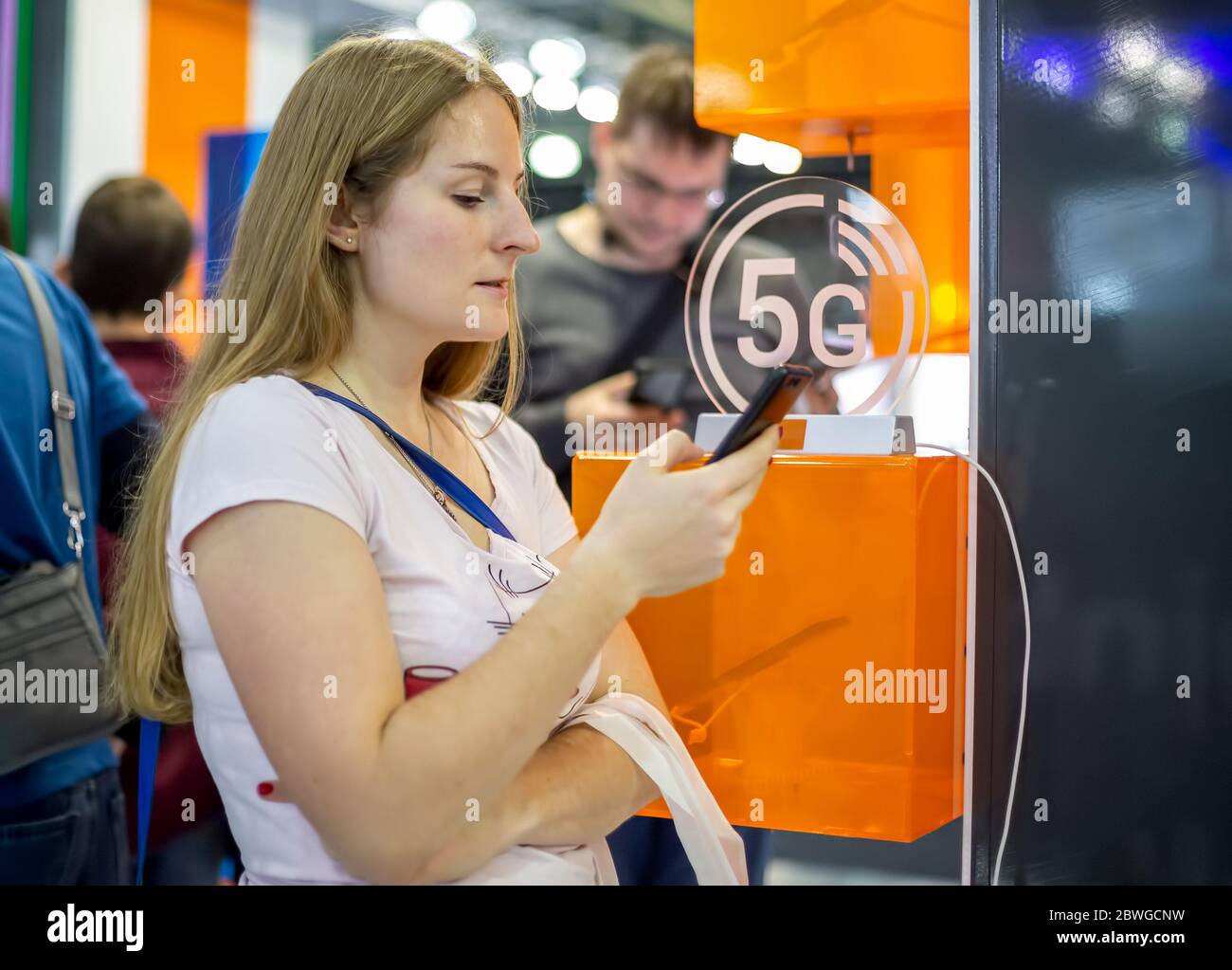 young caucasian girl surfs the internet on a smartphone on the background of the 5g icon xiaomi. blur background, soft focus Stock Photo