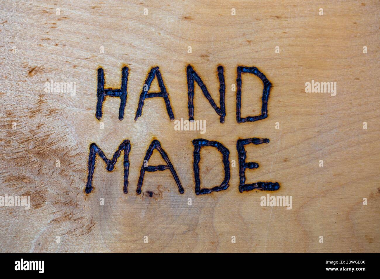 the word hand made handwritten on flat wooden background with electrical woodburner Stock Photo