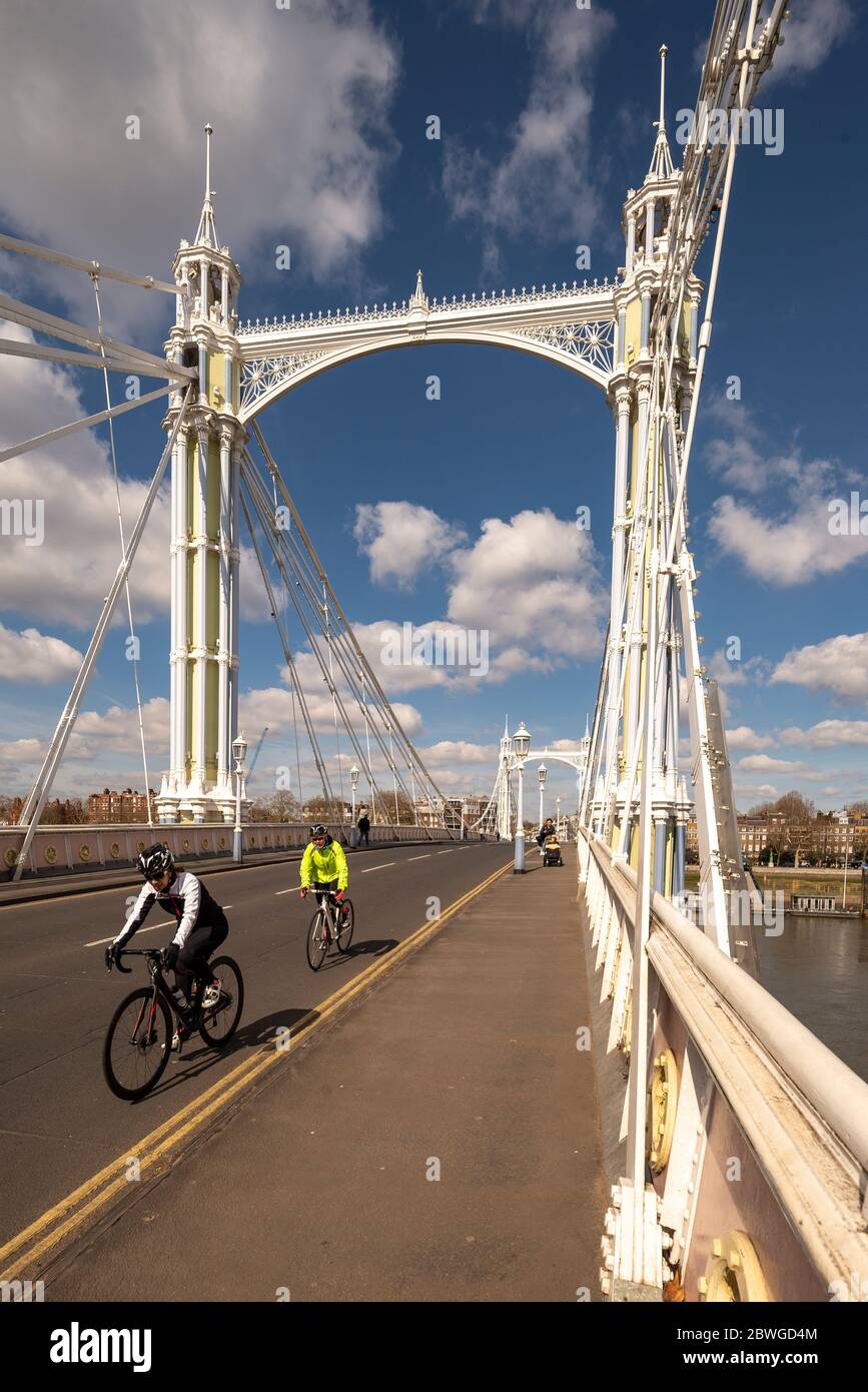 Cyclists ride across The Albert Bridge over the River Thames, Chelsea, London. A grade 2 listed building and unique road bridge with period features Stock Photo