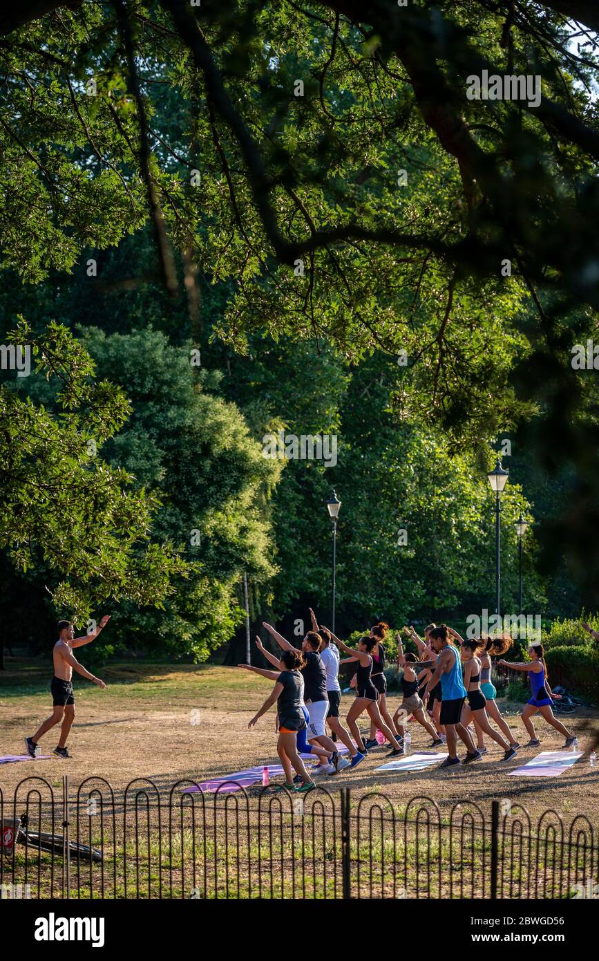 Fitness instructor and people exercising  outdoors on the grass in Battersea Park Royal Borough of Kensington and Chelsea London Stock Photo