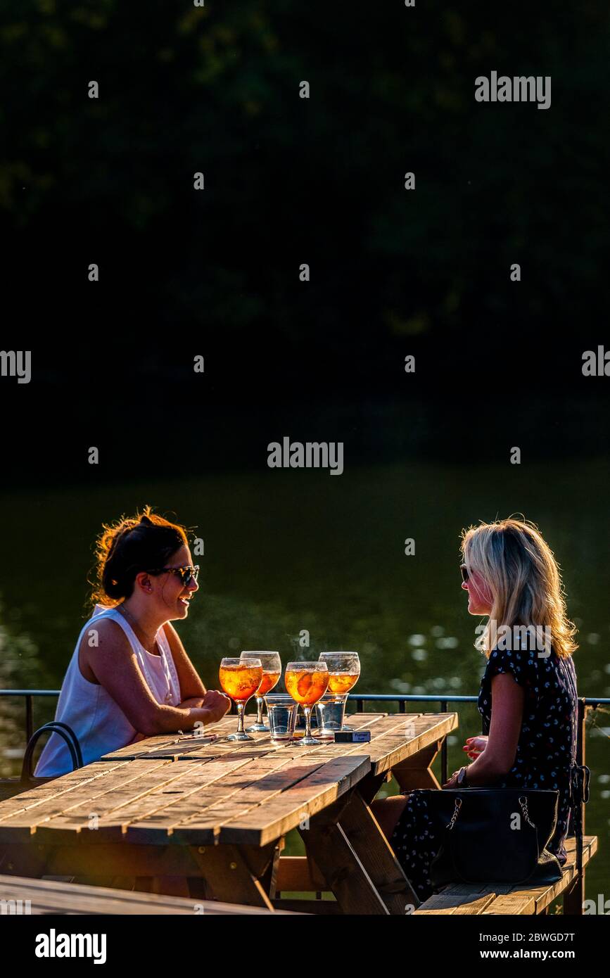 Two ladies enjoying aparol spritz cocktails in the summer evening sun at a beer garden in Battersea park Royal Borough of Kensington and Chelsea Stock Photo