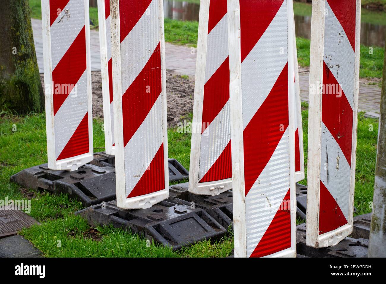 Red & white reflective roadblock barricades for directing traffic during roadwork or maintenance in a construction zone. Concept of traffic safety Stock Photo