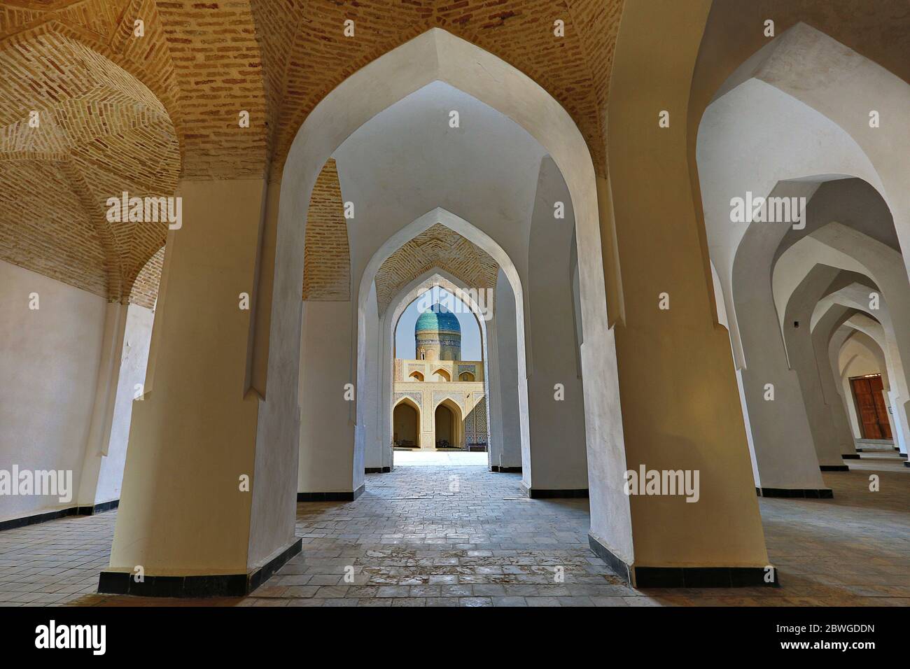 Arches of Poi Kalon mosque and its blue dome through archways, in Bukhara, Uzbekistan Stock Photo