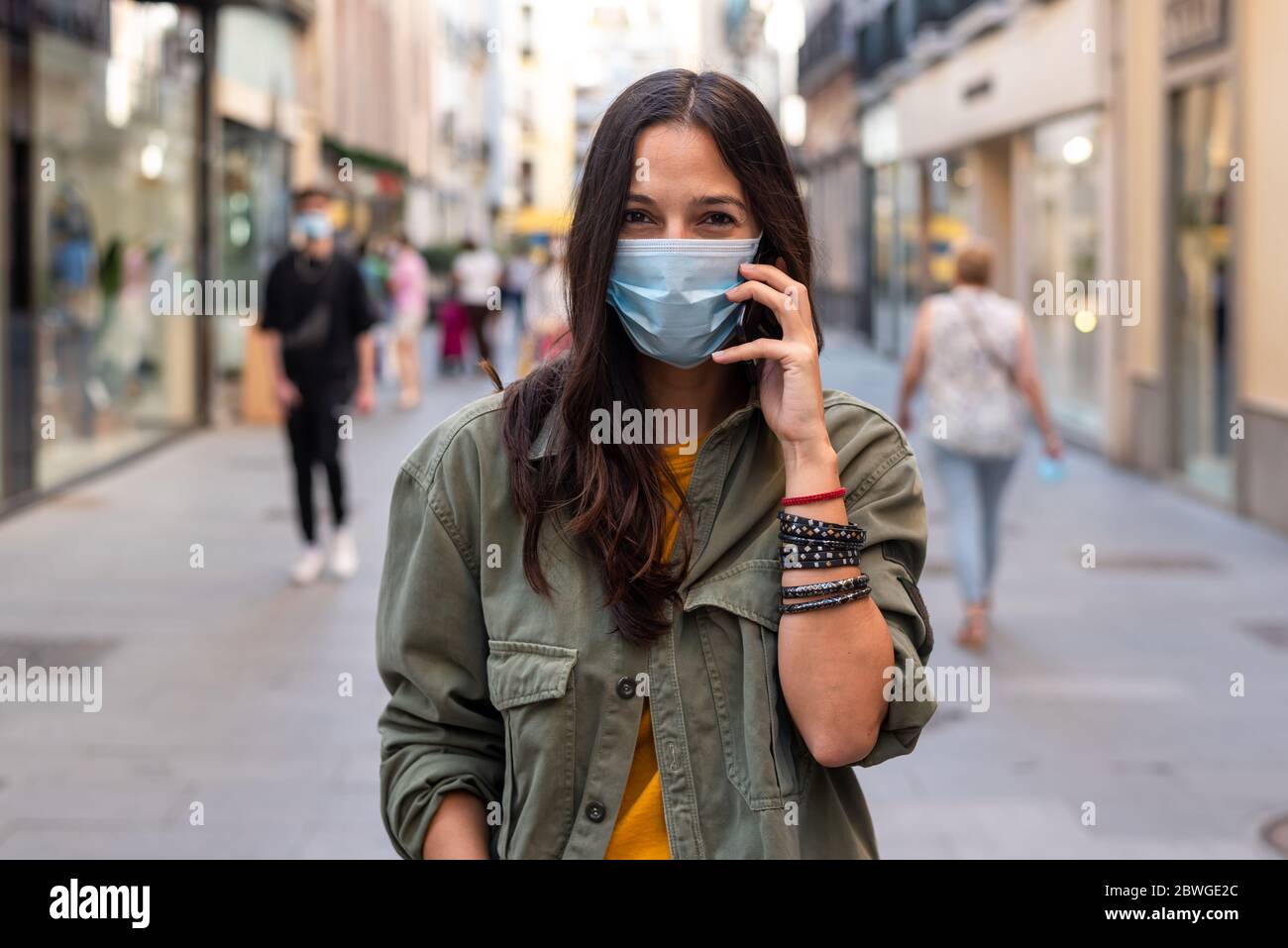 Woman wearing a protective mask on her face while using mobile phone in the street Stock Photo