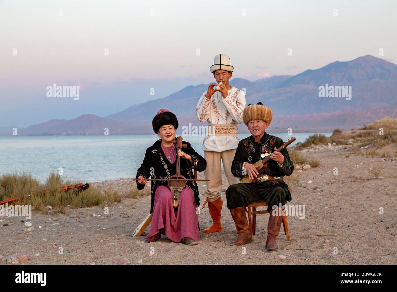Kyrgyz musicians playing traditional instruments. Man in white plays Choor, lady plays Kyl Kiak, man sitting plays Komuz, in Issyik Kul, Kyrgyzstan Stock Photo