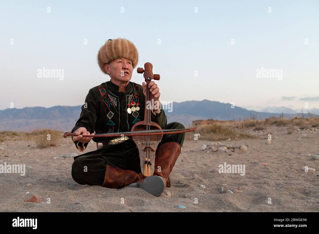 Kyrgyz musician playing traditional musical instrument known as Komuz, in Issyk Kul, Kyrgyzstan Stock Photo