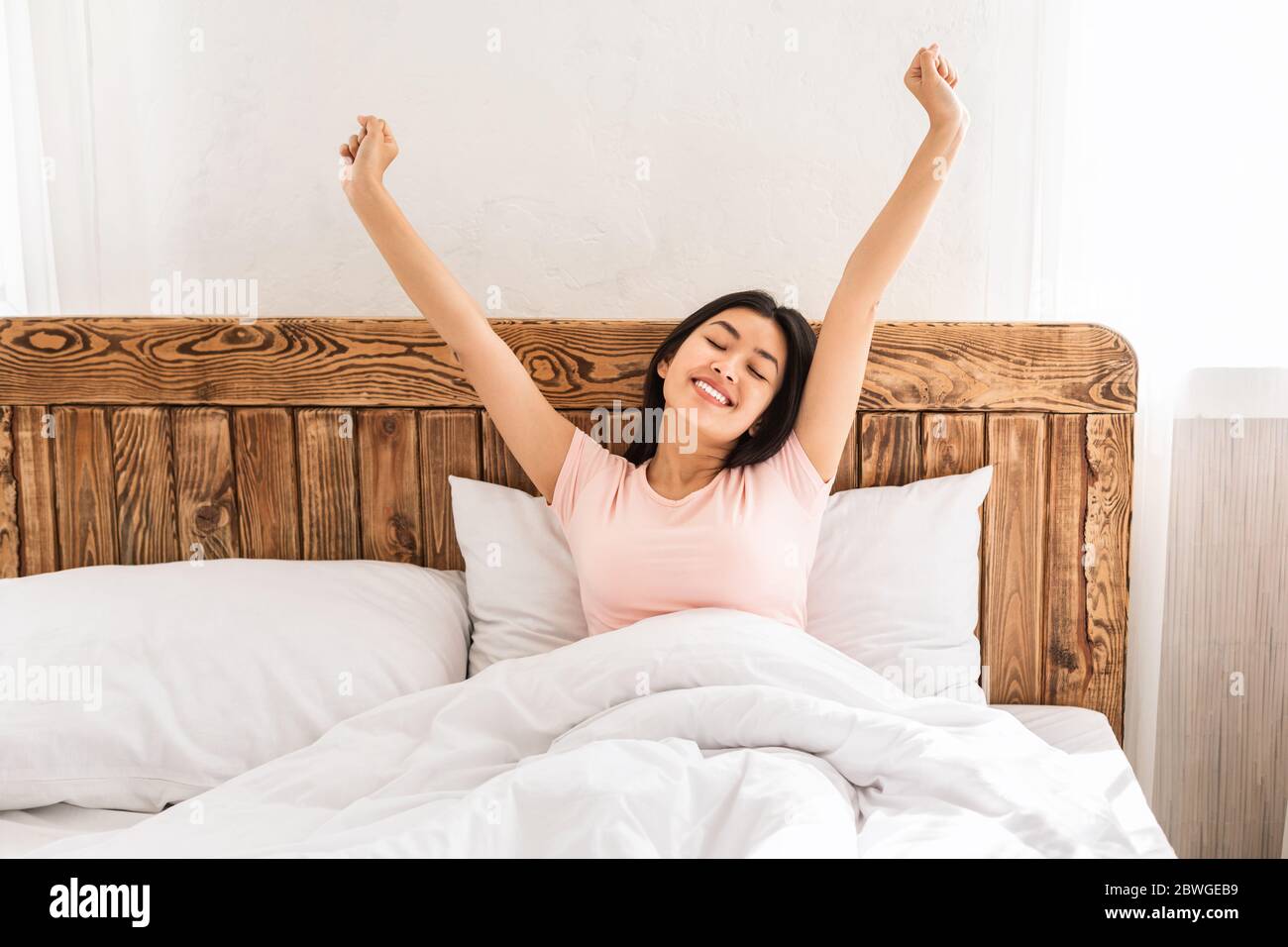 Joyful Woman Waking Up Stretching Hands Enjoying Morning At Home Stock Photo
