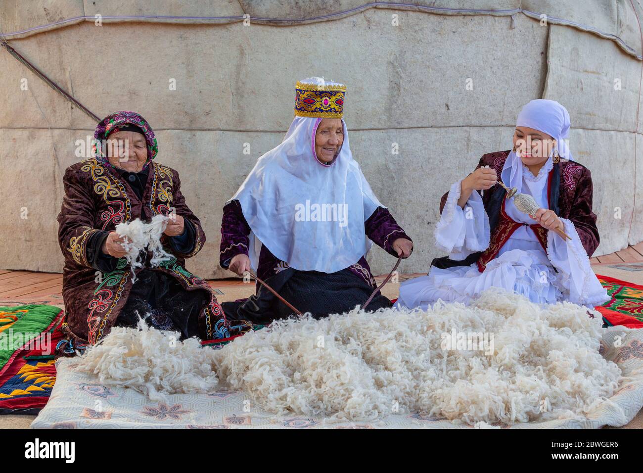 Kazakh elderly women making the wool fluffy and spinning it, in Almaty, Kazakhstan Stock Photo
