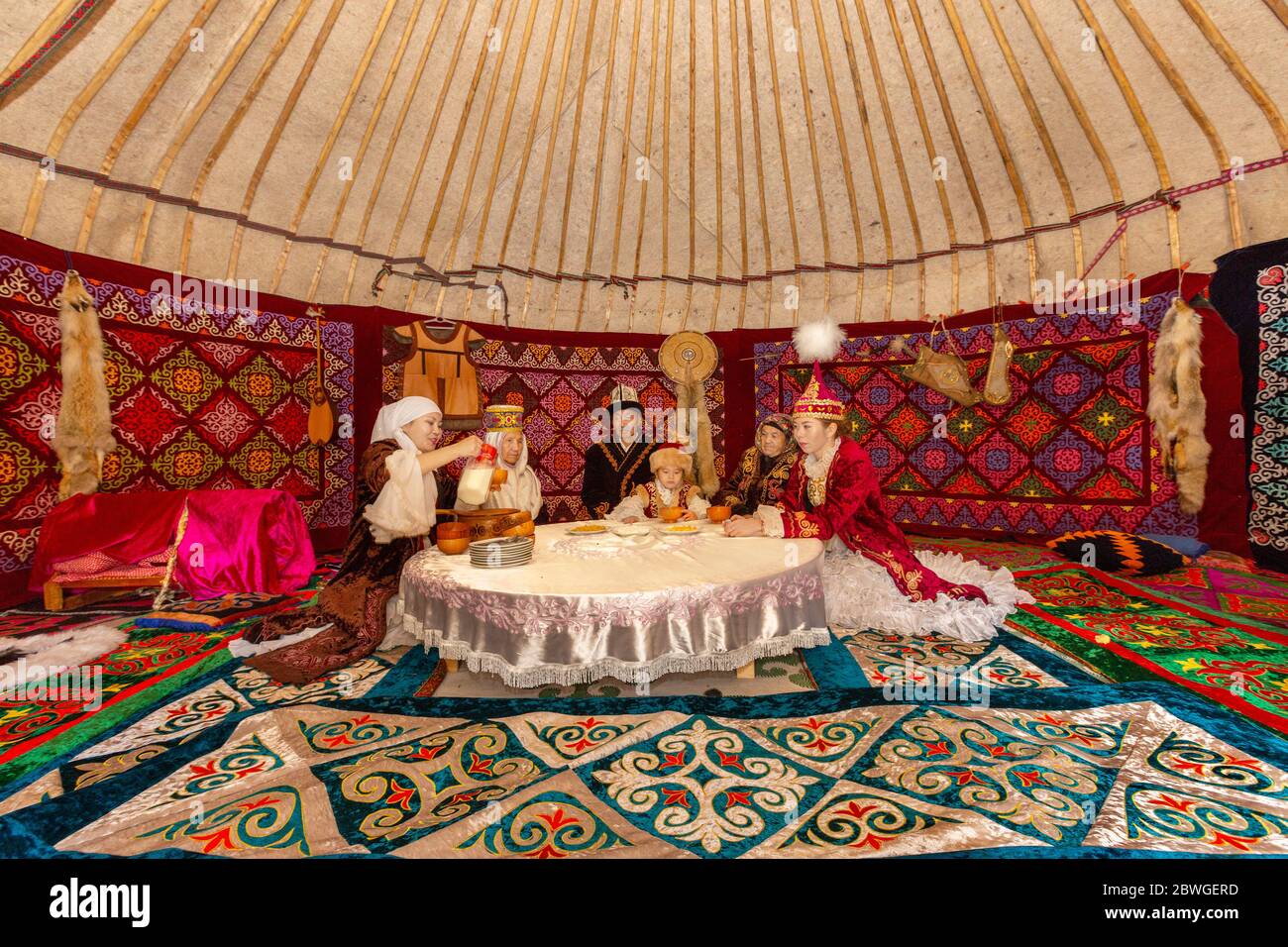 Kazakh people in traditional costumes in a nomadic tent known as yurt, drinking Kymyz, traditional drink made with horse milk, in Almaty, Kazakhstan Stock Photo