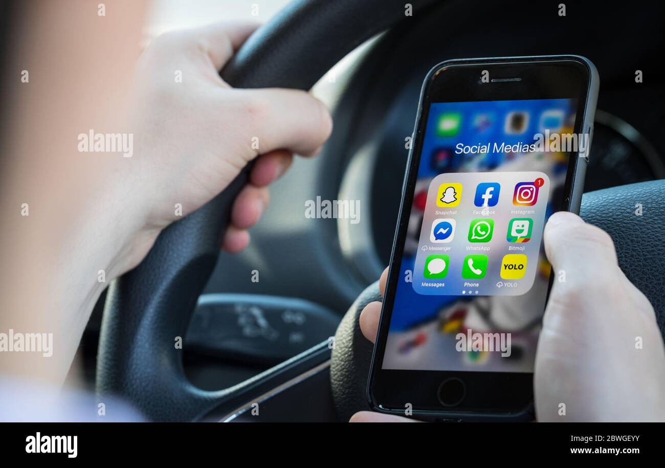 Teen driver texting and looking at social media on his phone whilst driving in the UK. (picture posed by model) Stock Photo