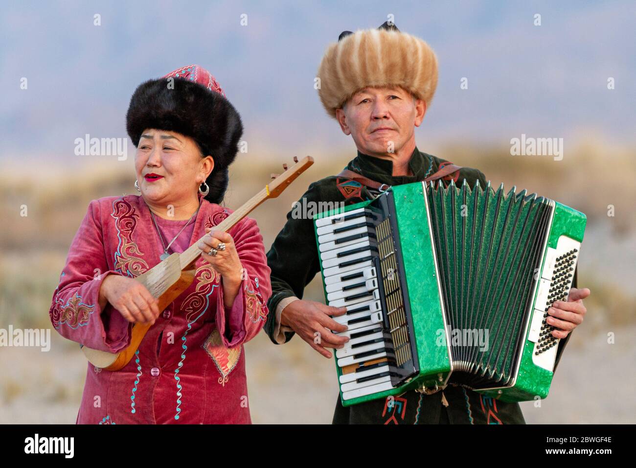 Kyrgyz musicians playing musical instruments. Man plays accordion and woman plays traditional instrument known as Komuz, in Issyik Kul, Kyrgyzstan Stock Photo