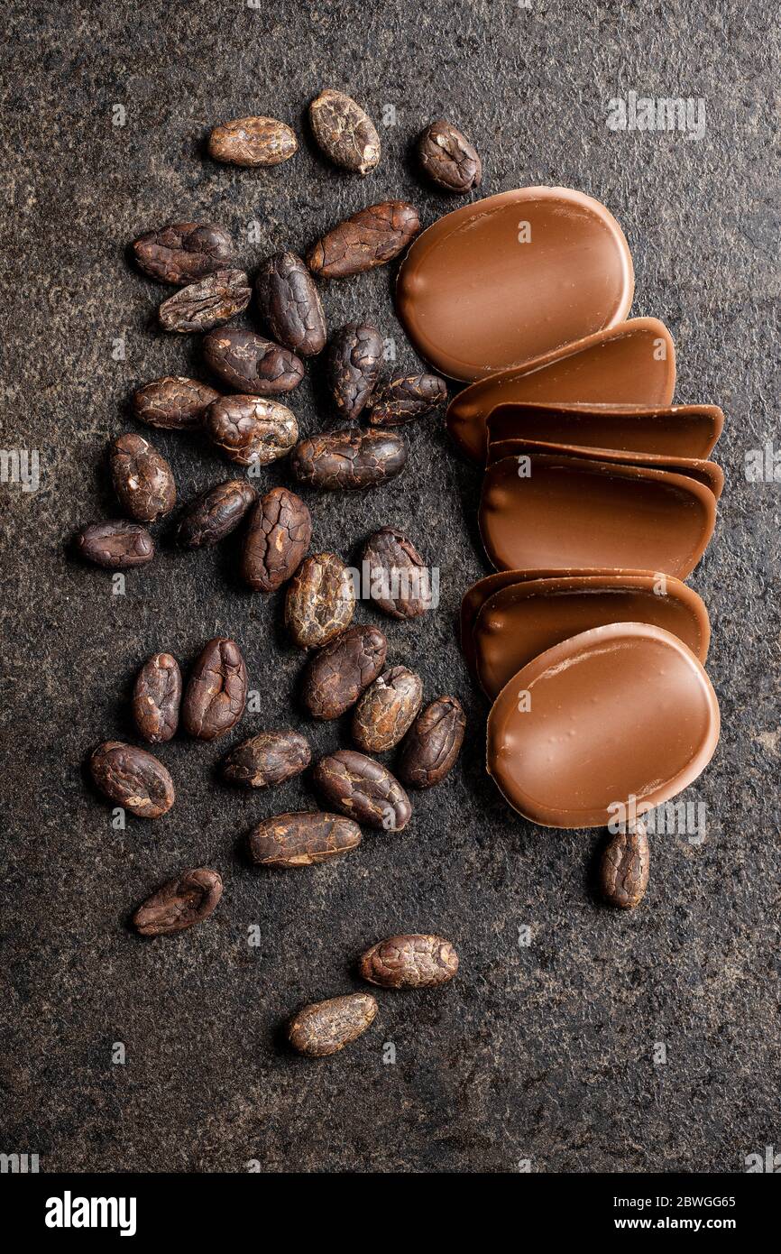 Dark chocolate chips and cocoa beans on black table. Top view Stock Photo Alamy