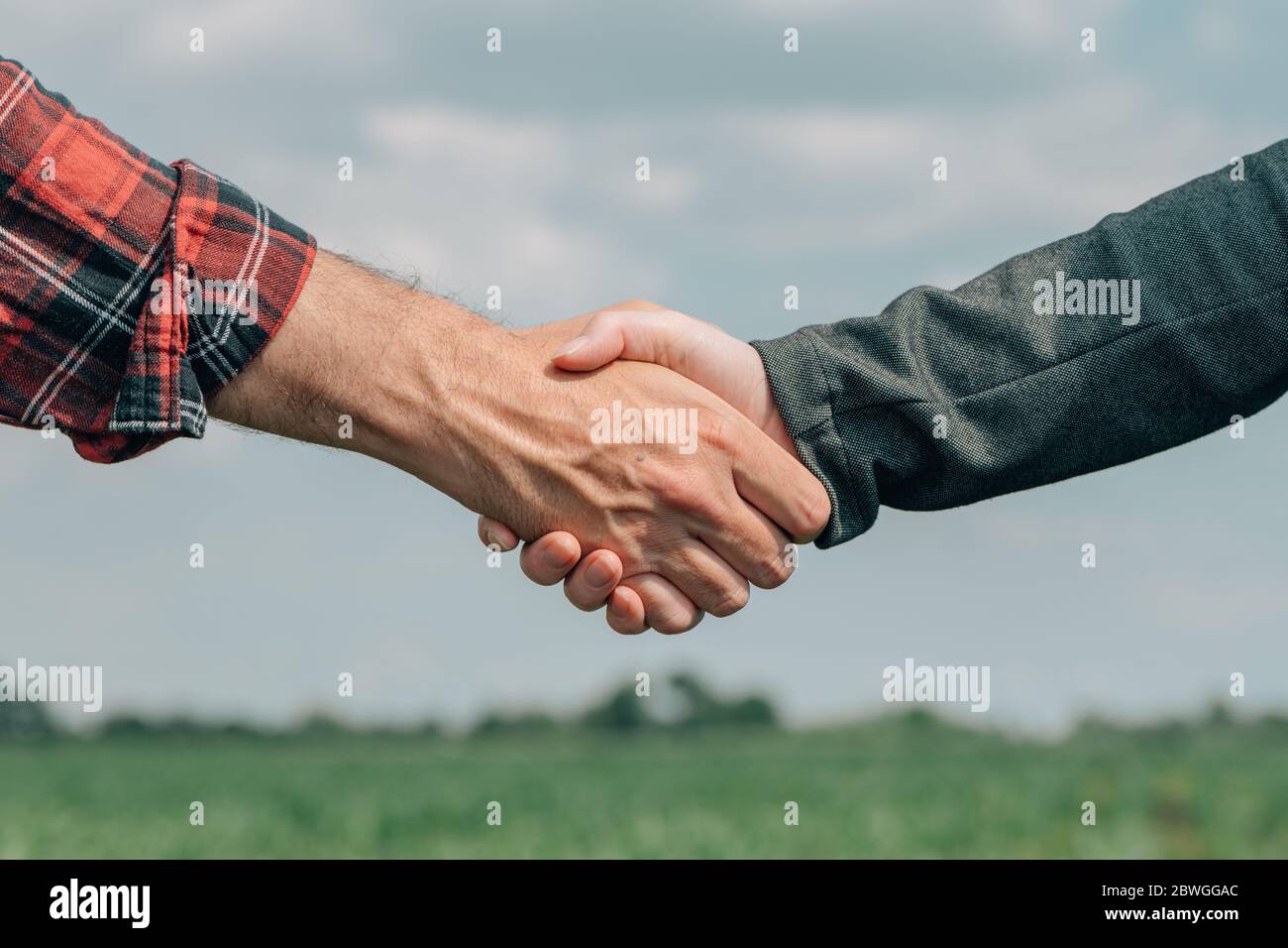 Mortgage loan officer and farmer shaking hands upon reaching an