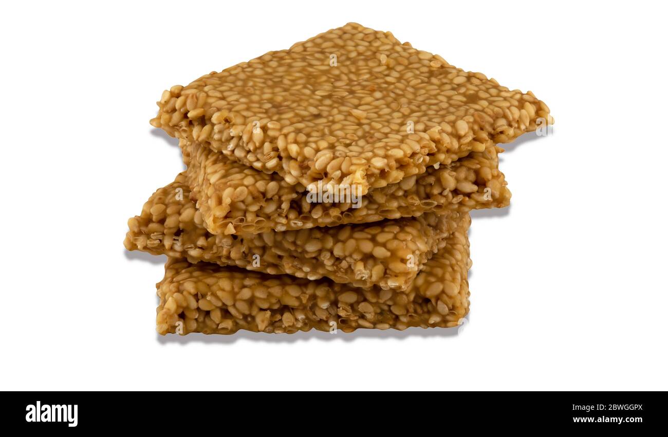 Til chikki on white background is an Indian sweet dish made with jaggery and sesame seeds. Stock Photo