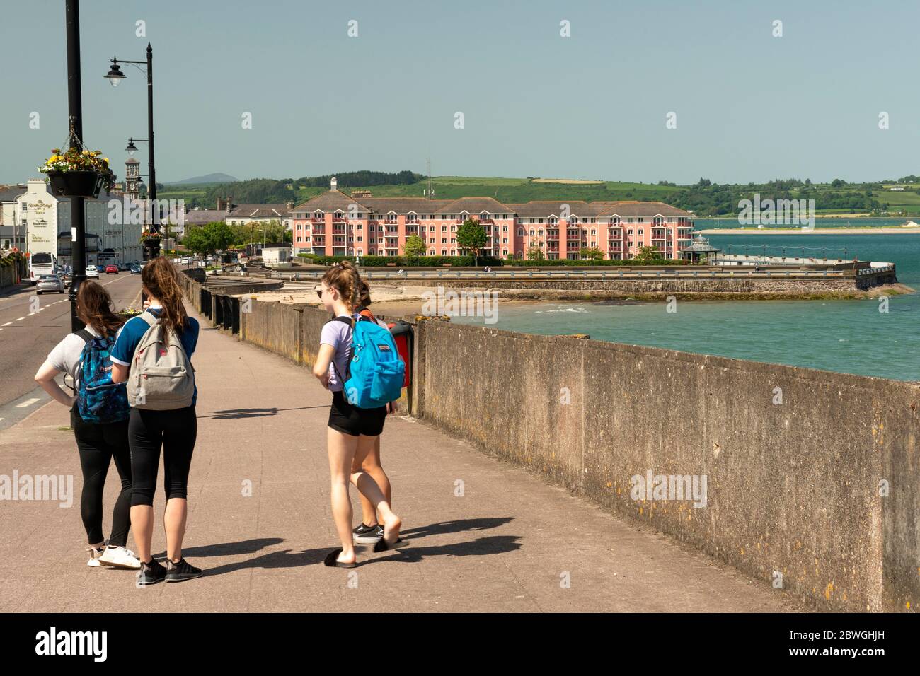 Group of teenagers girls with backpacks hanging around carefree in Lighthouse Hill Street on sunny summer afternoon in Youghal, County Cork, Ireland Stock Photo