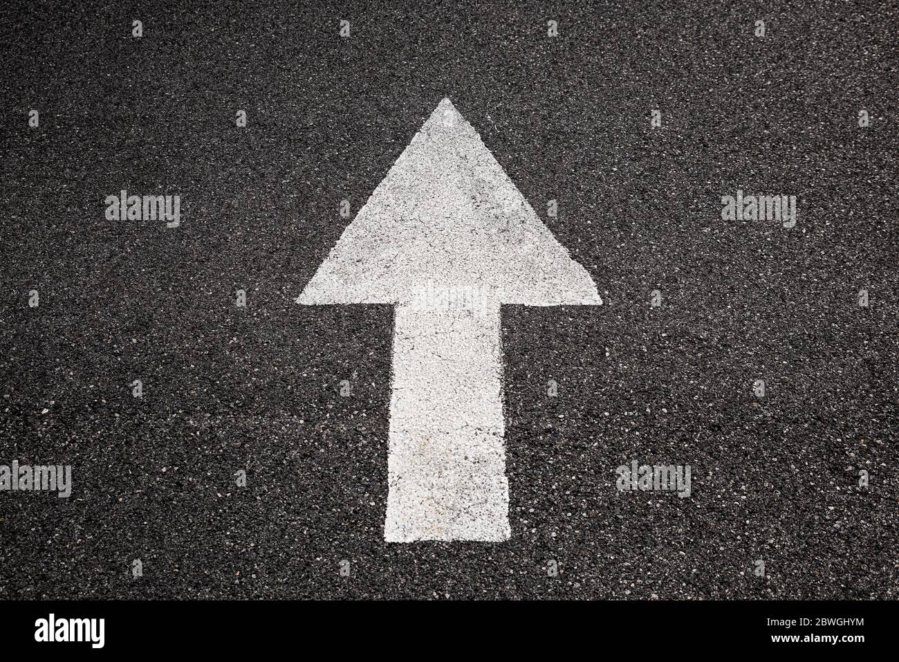 White arrow on black asphalt pointing forward Stock Photo