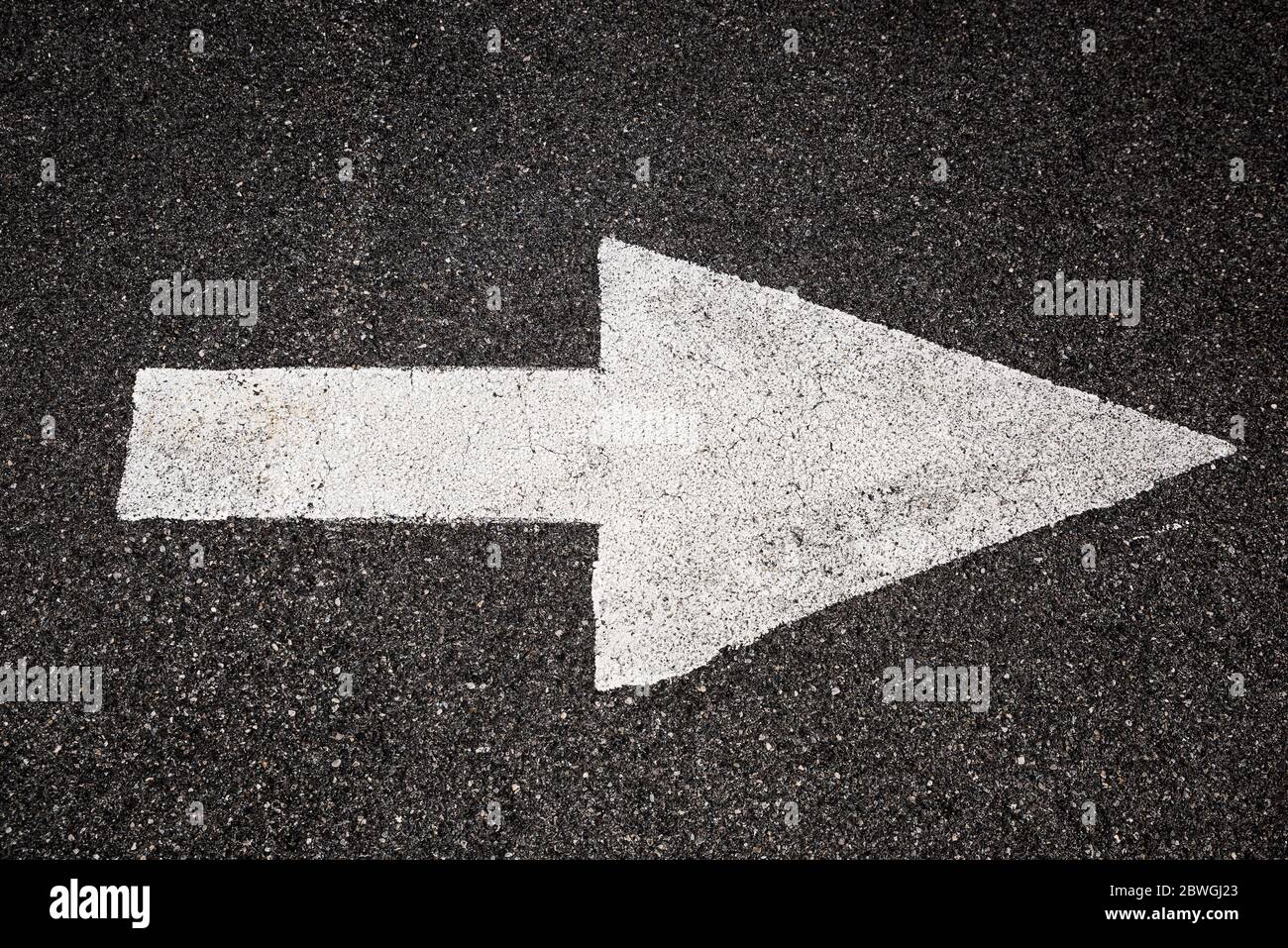 White arrow on black asphalt pointing to the right Stock Photo