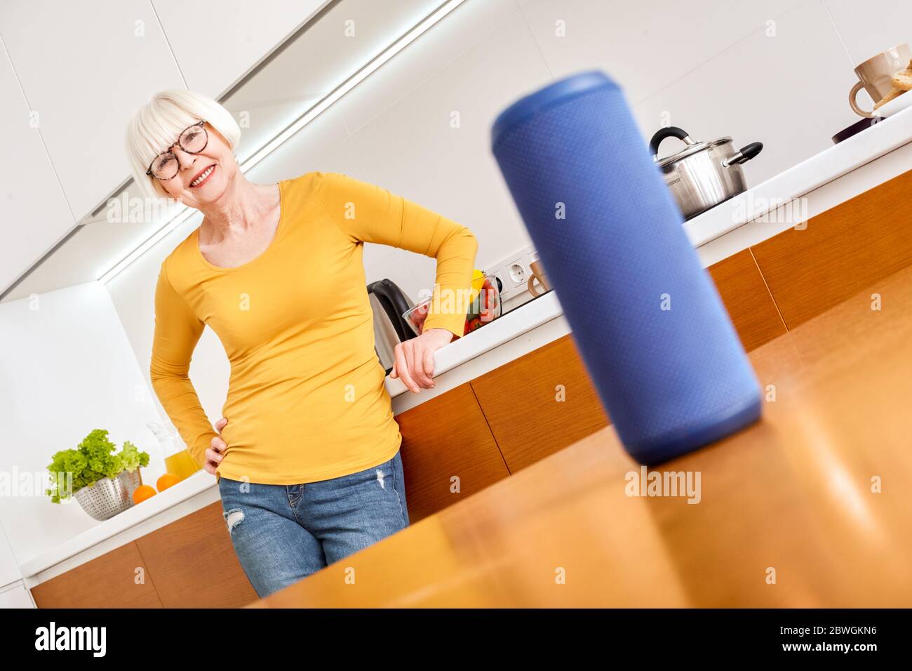 Mature aged woman using modern tablet computer and smart speaker Stock Photo