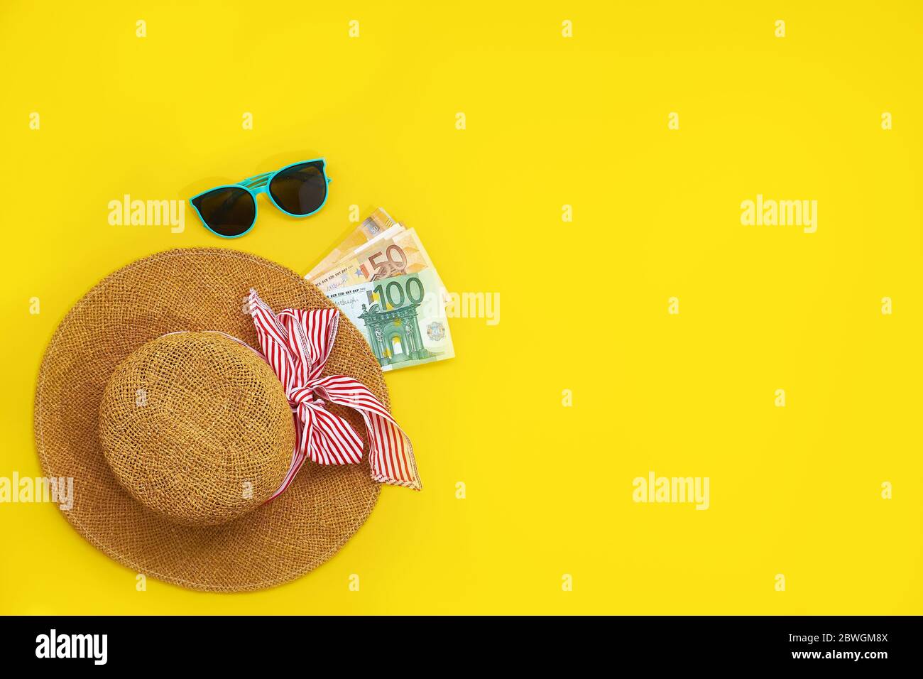 Straw hat with euro bills isolated on a yellow background. Top view flat lay. vacation cash expense concept Stock Photo