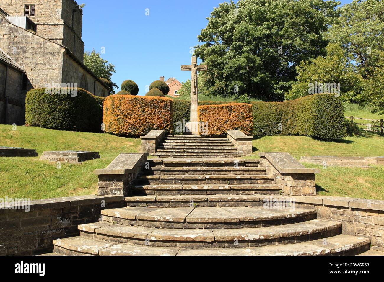 The churchyard of Kirby Underdale church in the Yorkshire wolds in summertime with steps leading to the statue of Christ on the cross Stock Photo