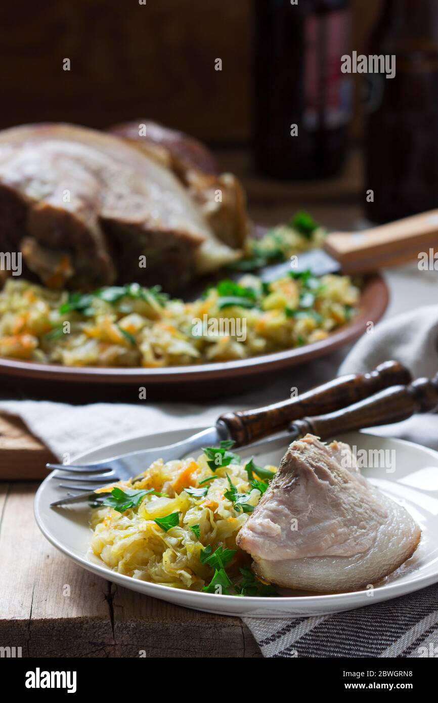 Baked pork knuckle served with stewed cabbage and beer. Rustic style. Stock Photo