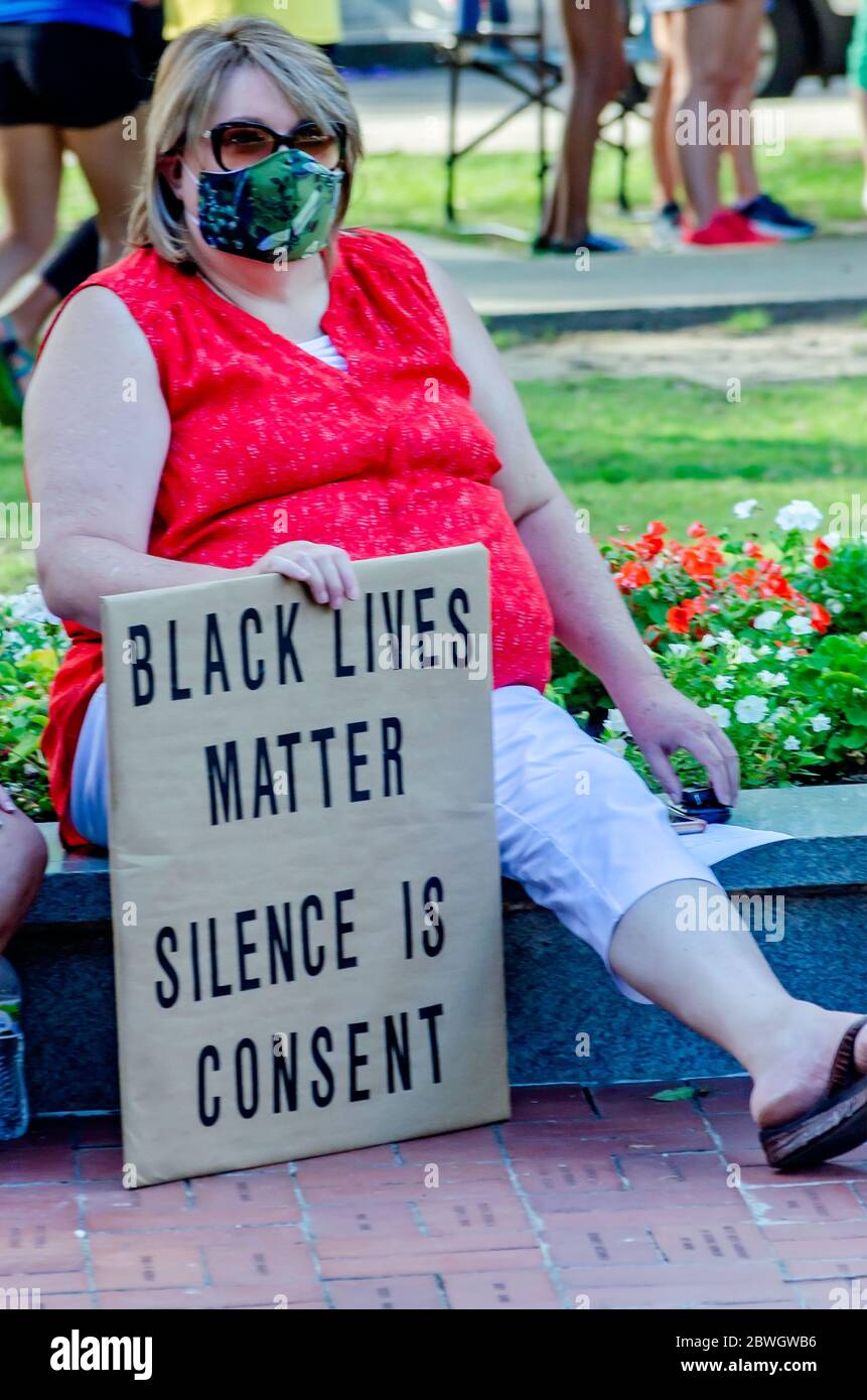 A woman holds a sign during a vigil for George Floyd at Cathedral Square, May 31, 2020, in Mobile, Alabama. Stock Photo