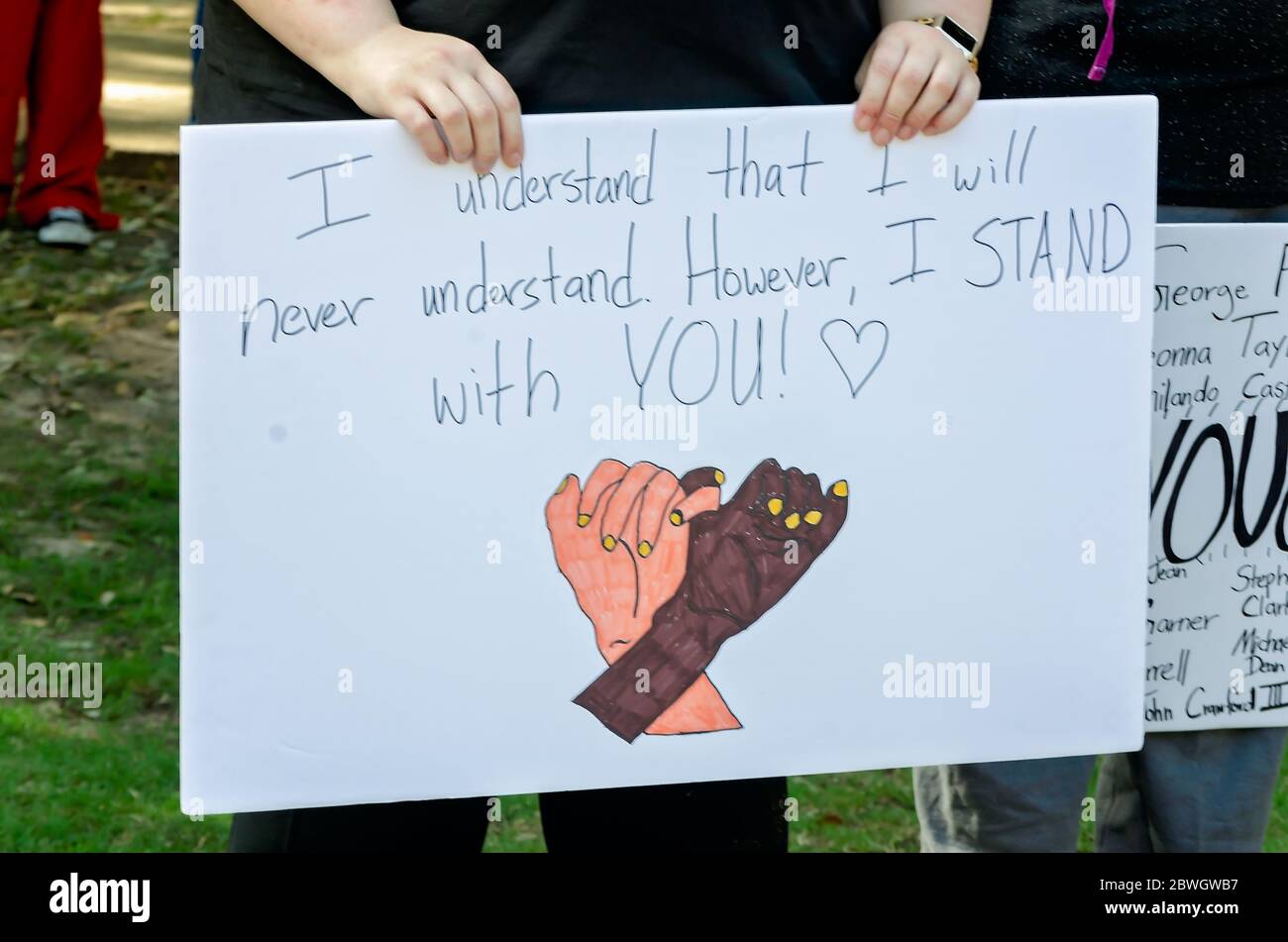 A white person holds a sign of support during a vigil for George Floyd at Cathedral Square, May 31, 2020, in Mobile, Alabama. Stock Photo