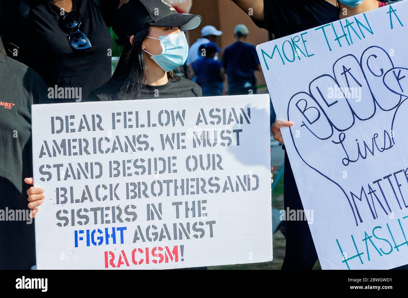 An Asian-American woman holds a sign during a vigil for George Floyd at Cathedral Square, May 31, 2020, in Mobile, Alabama. Stock Photo