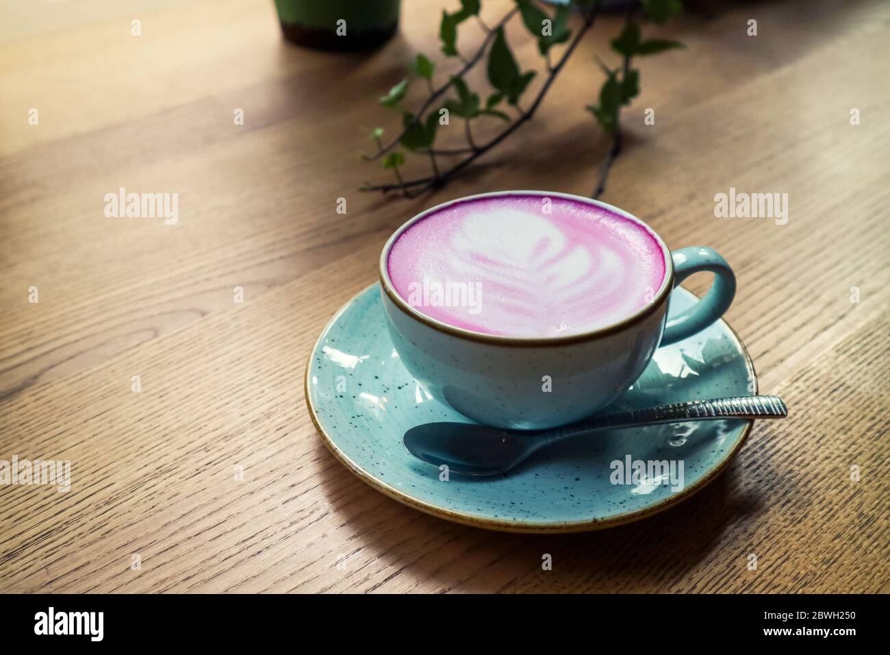 Cup of pink cappuccino in blue cup on wooden  table in a cafe closeup Stock Photo